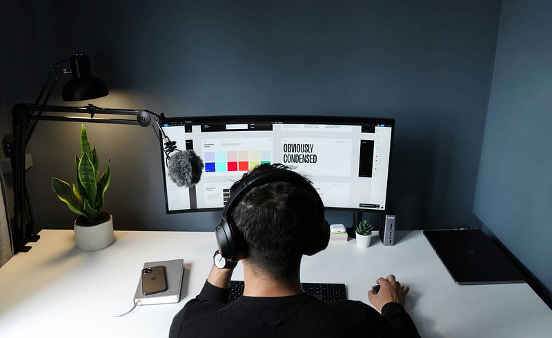 Man wearing headphones, focused while working on a computer screen. - Photo by Faizur Rehman on&nbsp;Unsplash